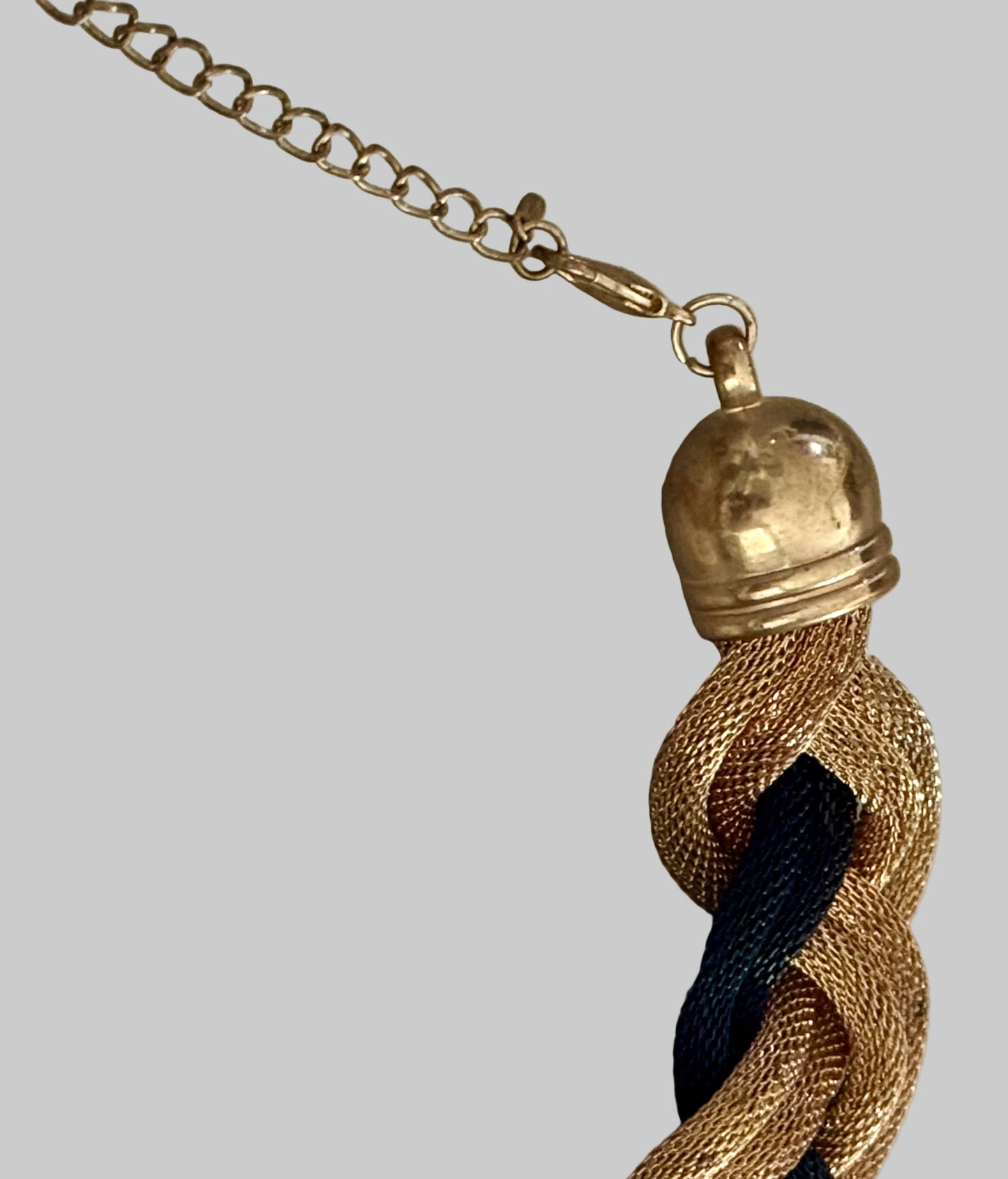 Close-up of a gold tassel with a chain on a light wooden surface