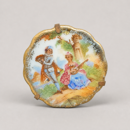 A scalloped-edge decorative plate or dish featuring a hand-painted classical scene of a man and woman in an outdoor landscape, displayed on a neutral light gray background.