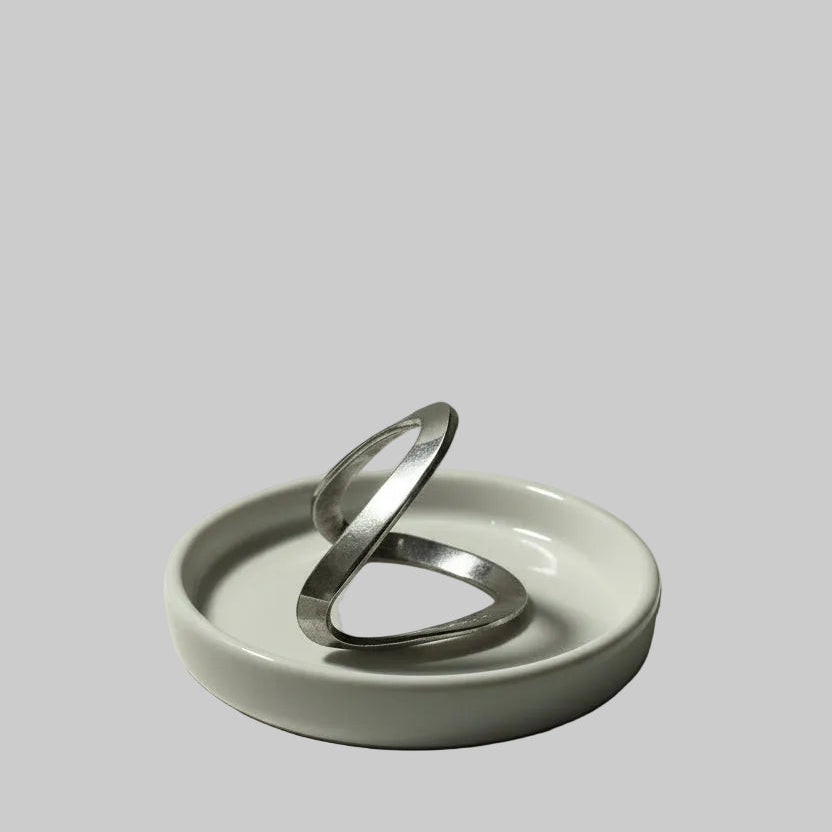 One silver chevron ring on a white dish against a gray background