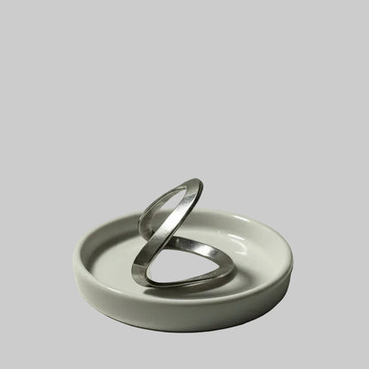 One silver chevron ring on a white dish against a gray background