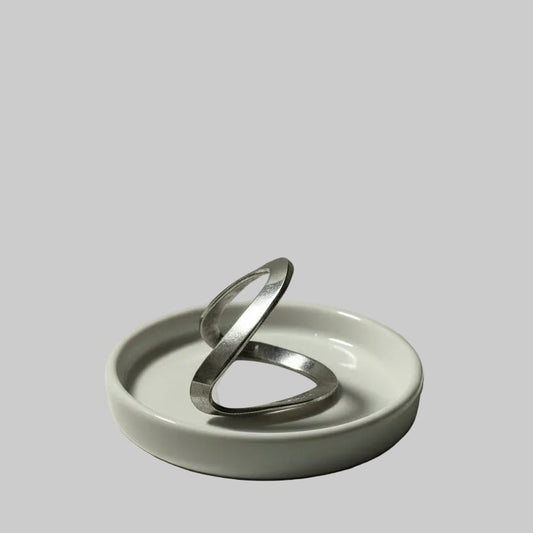 One silver chevron ring on a white dish against a gray background