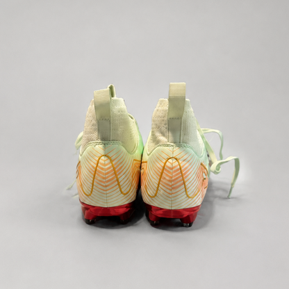 A pair of Nike soccer cleats shown from the back, featuring a light green and white textured upper with orange wave patterns, red midsoles, and light green laces on a neutral gray background.