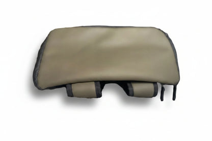 A beige massage pillow with black trim and adjustable straps, resting on a textured light gray blanket in a blurred indoor setting.
