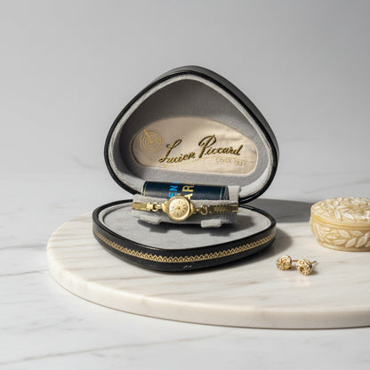 Gold watch in a Lucien Piccard box on a light surface.