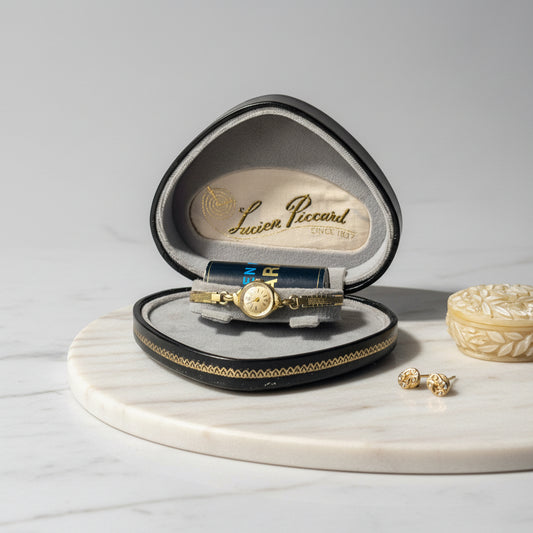 Gold watch in a Lucien Piccard box on a light surface.