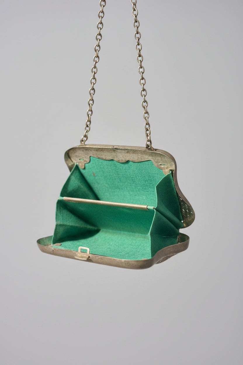 Vintage green handbag with silver chain strap on a neutral background