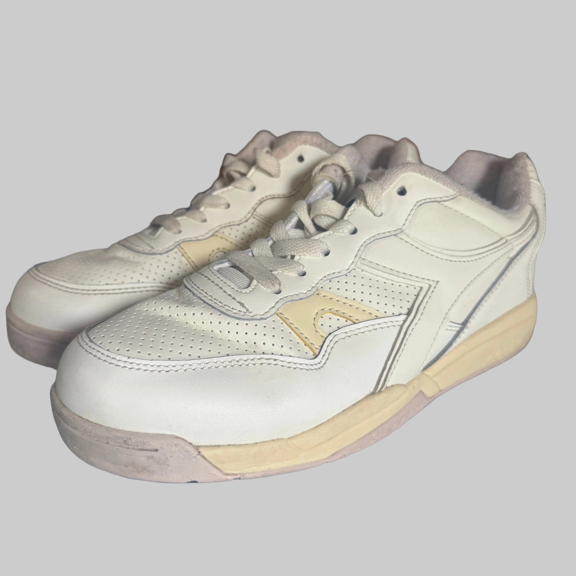 White sneakers with beige soles on a white surface, blurred background