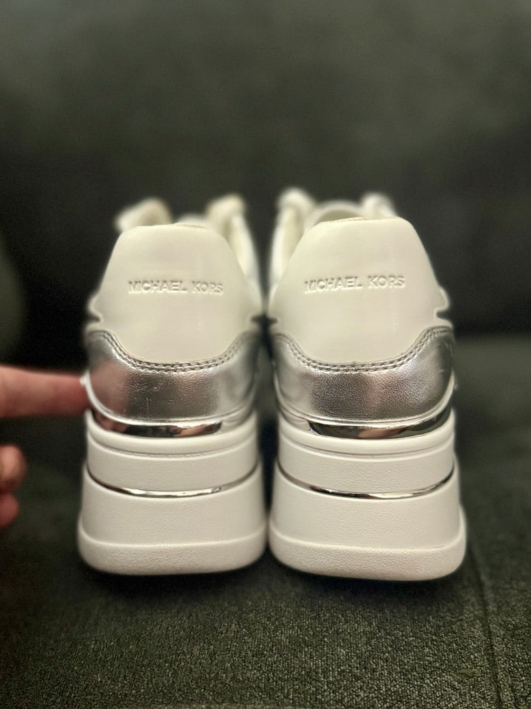 White sneakers with silver accents on a dark background