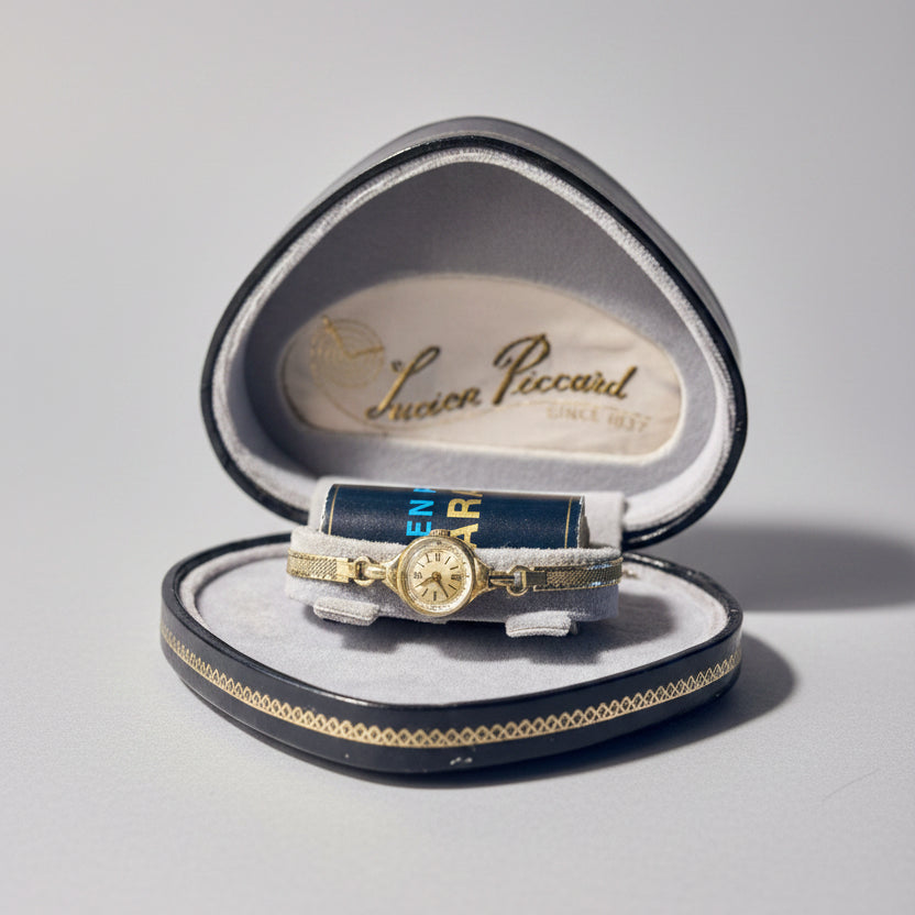Gold ring in an open jewelry box with 'Lucien Piccard' branding on a blurred background.