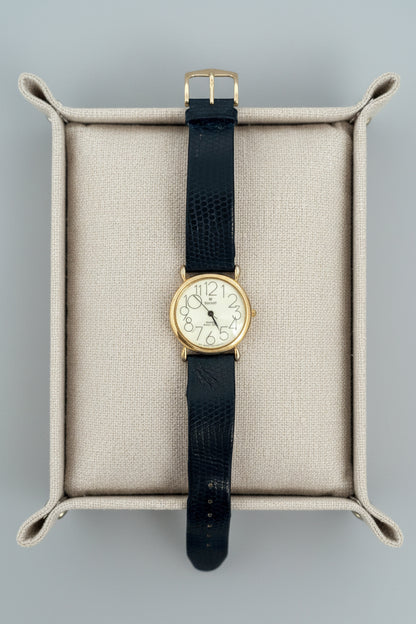 Vintage watch with black strap on a textured surface