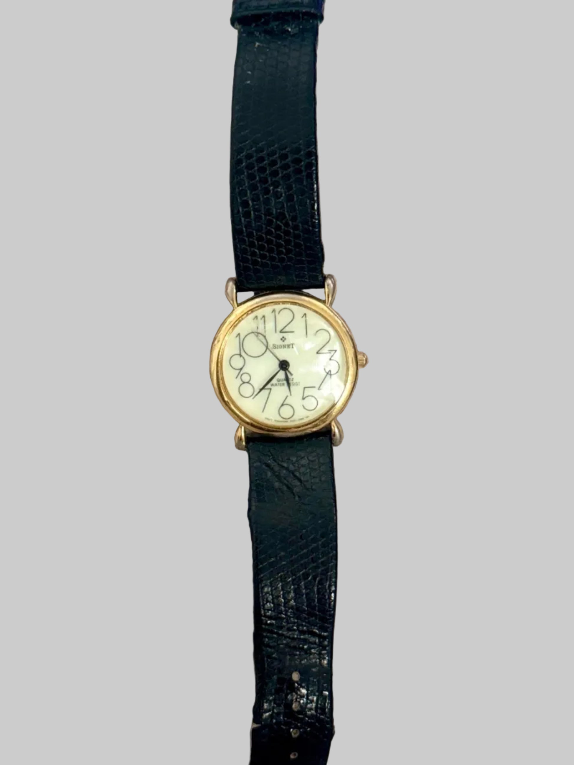 Vintage watch with black strap on a textured surface