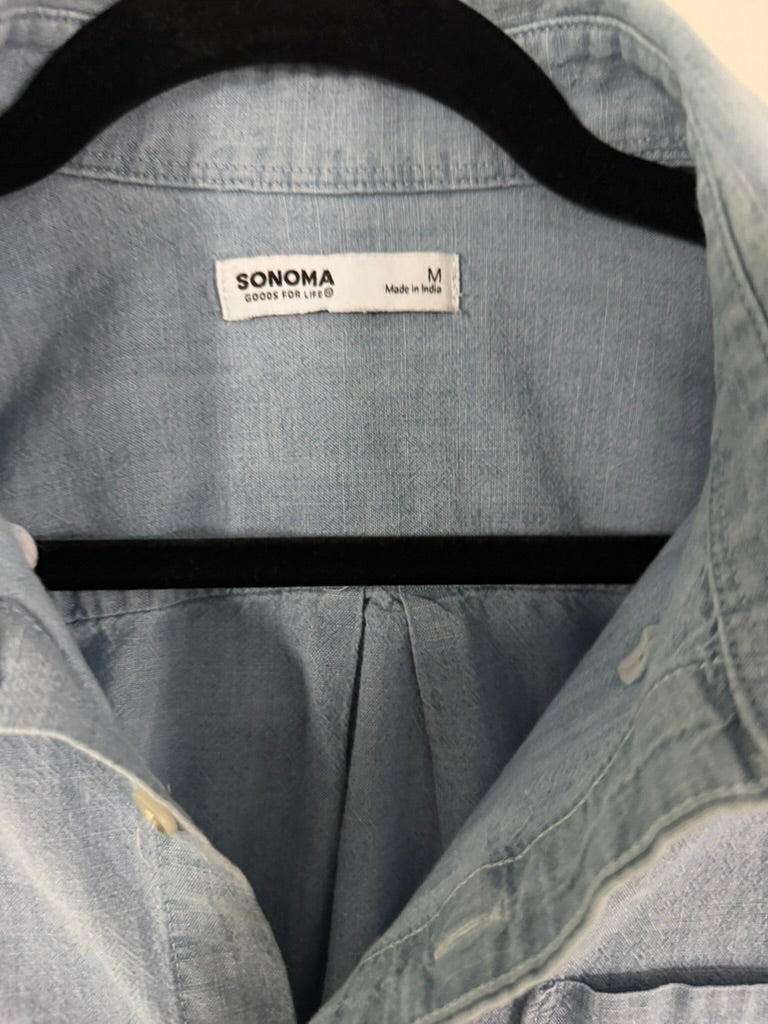 Close-up of a light blue denim Sonoma shirt on a black hanger, showing the brand label and collar area.