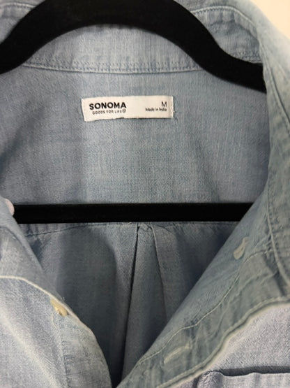 Close-up of a light blue denim Sonoma shirt on a black hanger, showing the brand label and collar area.