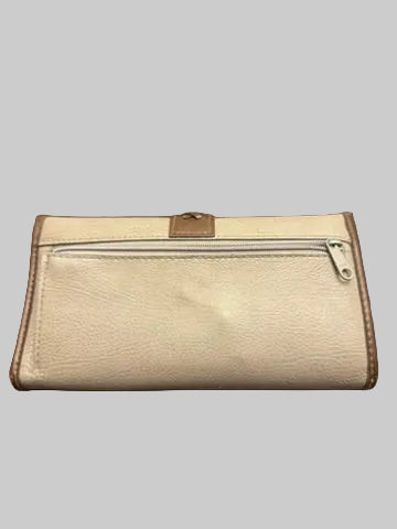 A beige pebbled leather wallet with brown trim and a silver zipper, resting on a dark wood floor.