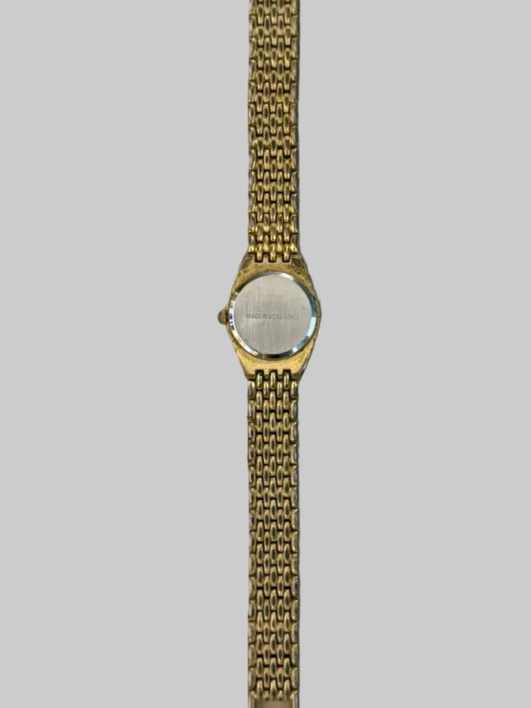 Back of Gold watch with a chain strap on a light gray surface