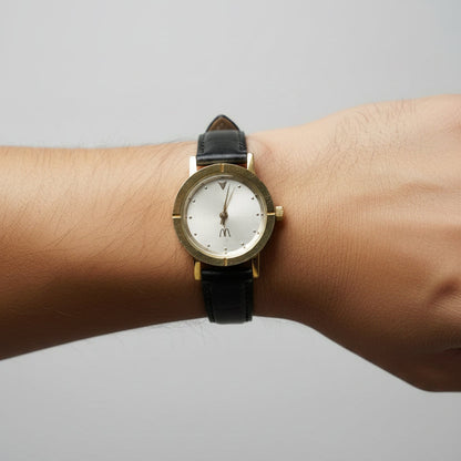 Wristwatch with black strap and gold accents on a textured gray background