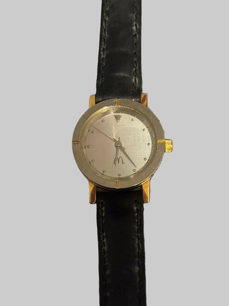 Wristwatch with black strap and gold accents on a textured gray background