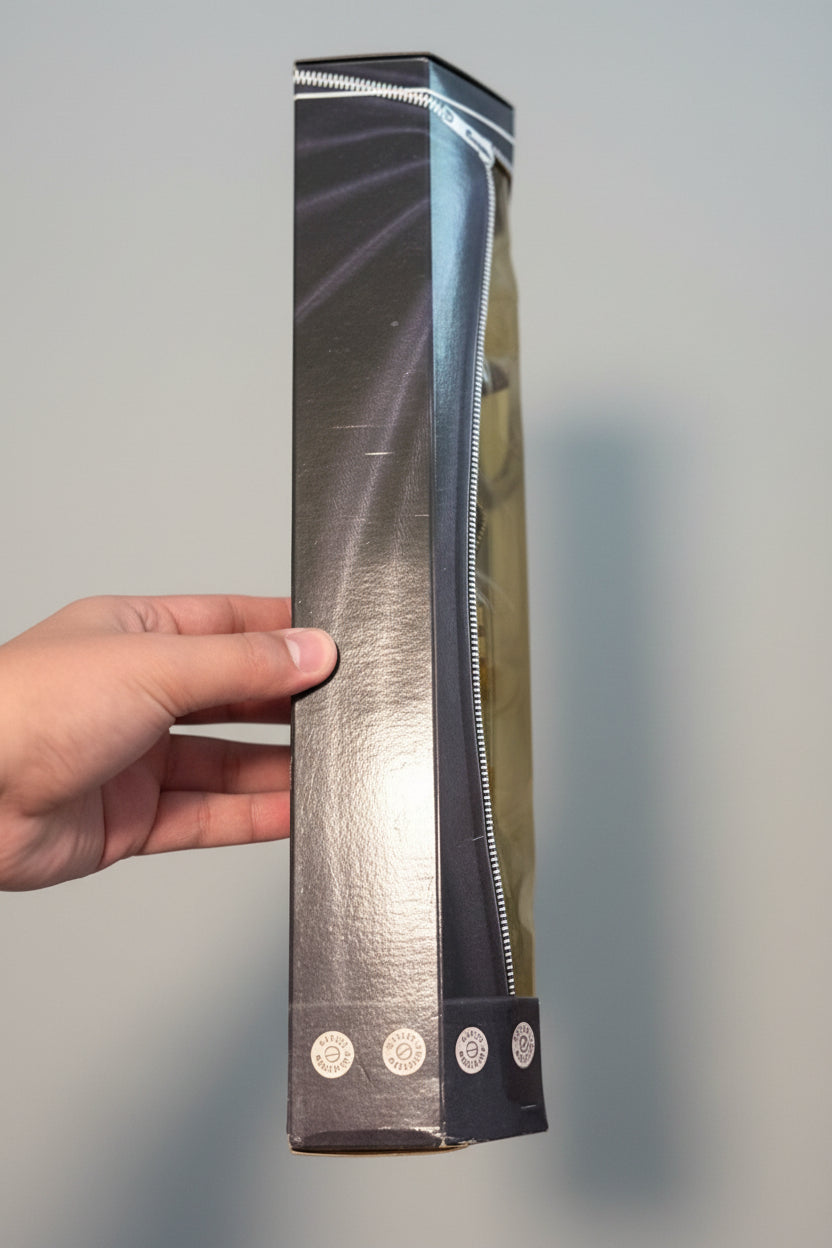 A hand holding a slim, black zippered pouch or sleeve with a glossy finish, standing vertically against a gray and white plaid fabric background.