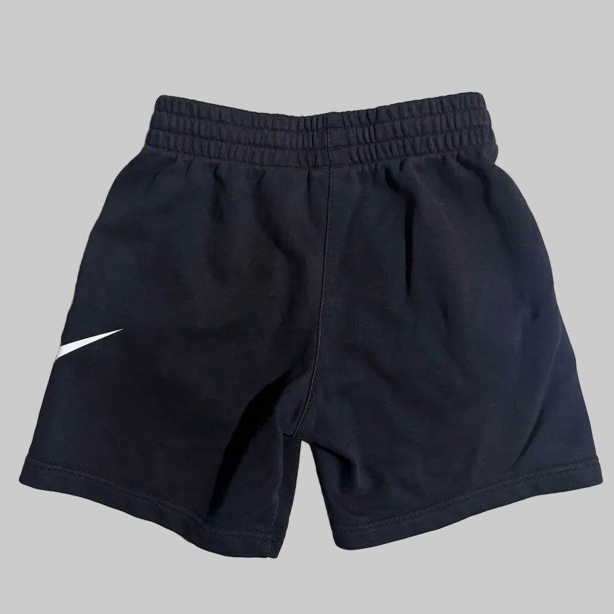 Navy blue athletic shorts with an elastic waistband and a white Nike swoosh logo on the left leg, shown against a solid gray background.