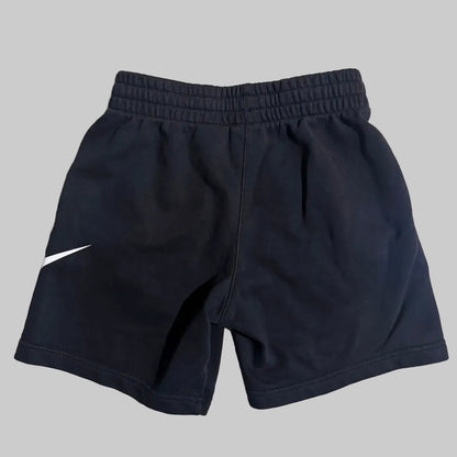 Navy blue athletic shorts with an elastic waistband and a white Nike swoosh logo on the left leg, shown against a solid gray background.