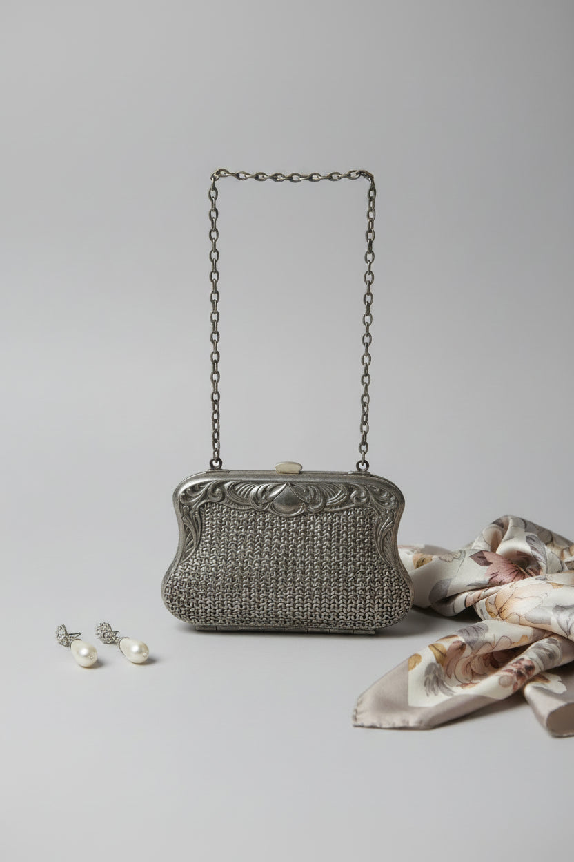 Vintage silver handbag with chain strap on a light gray background
