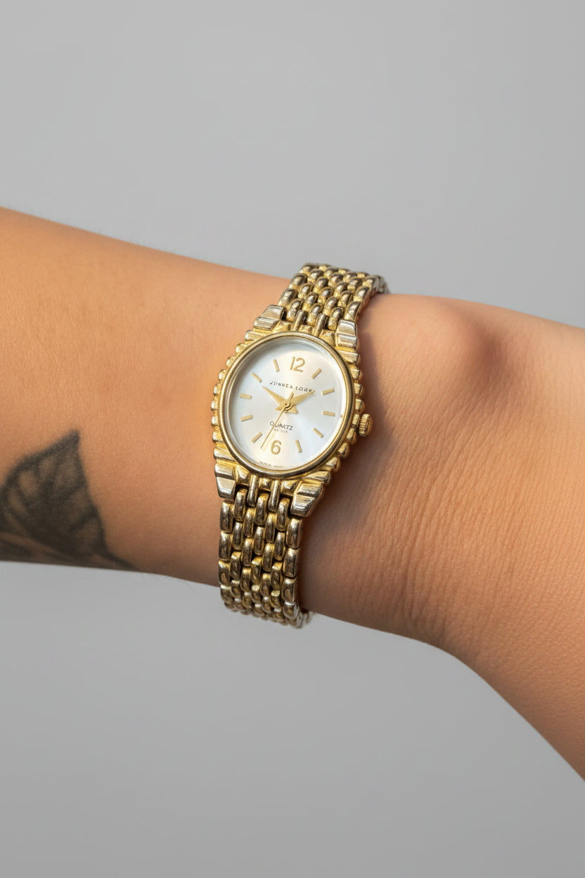Gold wristwatch on a person's wrist with a blurred background