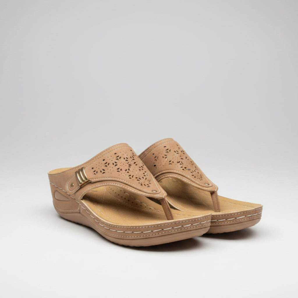 Pair of beige sandals on a wooden surface with a blurred indoor background