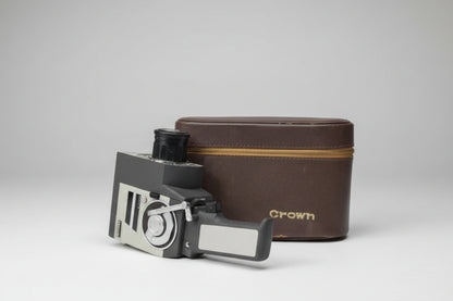 Vintage film camera and leather case on a gray surface.