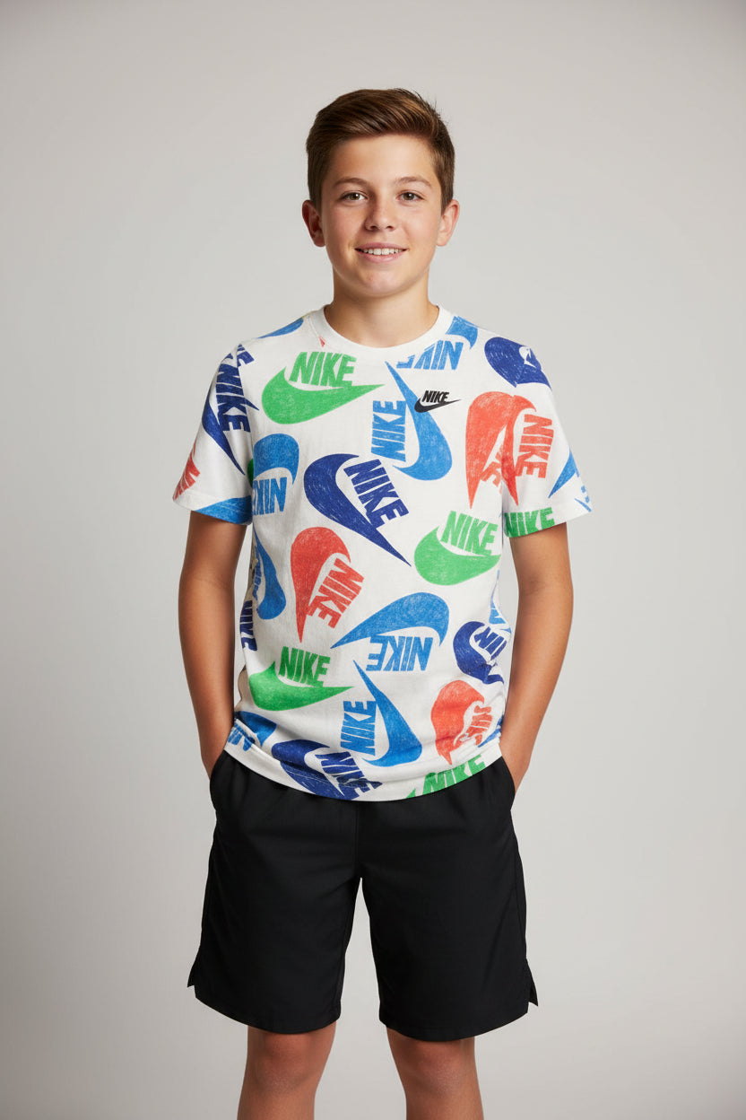 A vintage Nike short-sleeve t-shirt with a colorful all-over logo print, laid flat on a dark wooden floor.