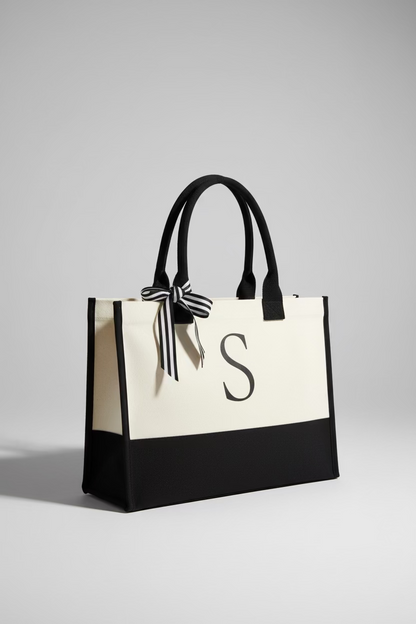 Black and white tote bag with a letter 'S' on a wooden surface