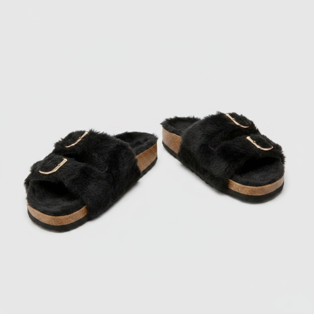 Black fuzzy slippers with gold buckles on a white background