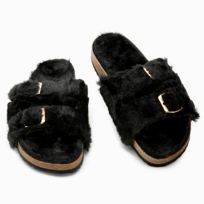 Black fuzzy slippers with gold buckles on a white background