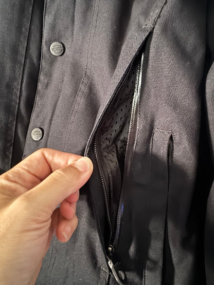 Close-up of a hand opening a zipper on a dark jacket.