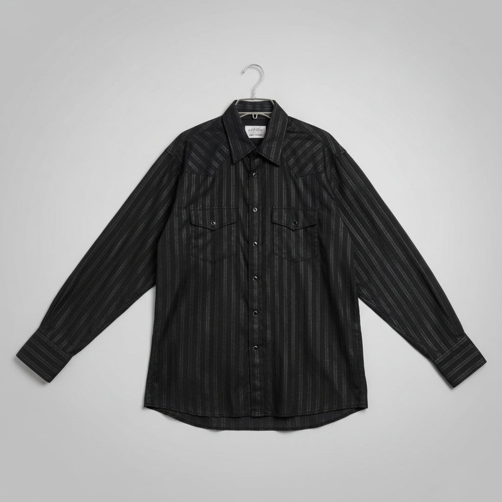 A black long-sleeve button-up shirt with a subtle vertical textured stripe pattern, laid flat on a beige carpet next to a measuring tape.