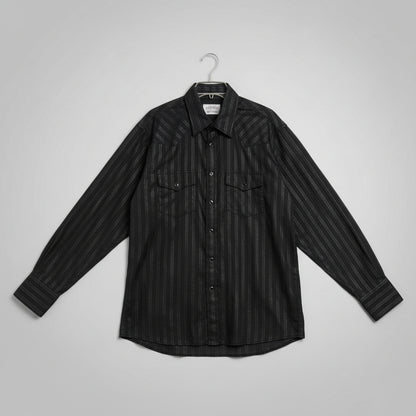 A black long-sleeve button-up shirt with a subtle vertical textured stripe pattern, laid flat on a beige carpet next to a measuring tape.