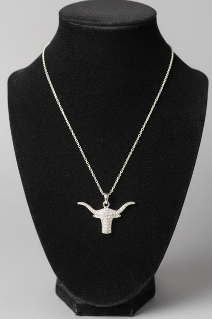 A silver-toned chain necklace with a longhorn-shaped pendant displayed on a black velvet jewelry bust, set against a blurred indoor background.