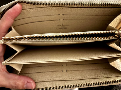 Beige wallet with a hand holding it open, showing the interior.