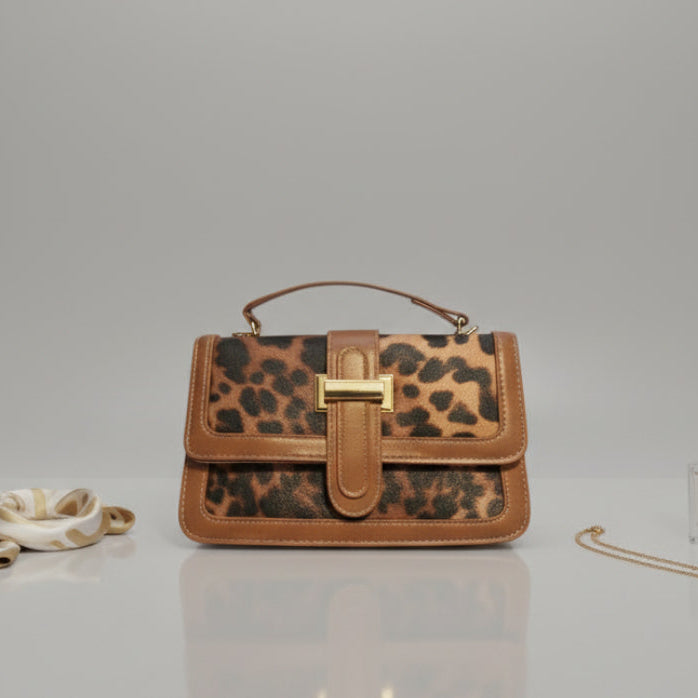 Leopard print handbag with brown leather accents on a light gray surface
