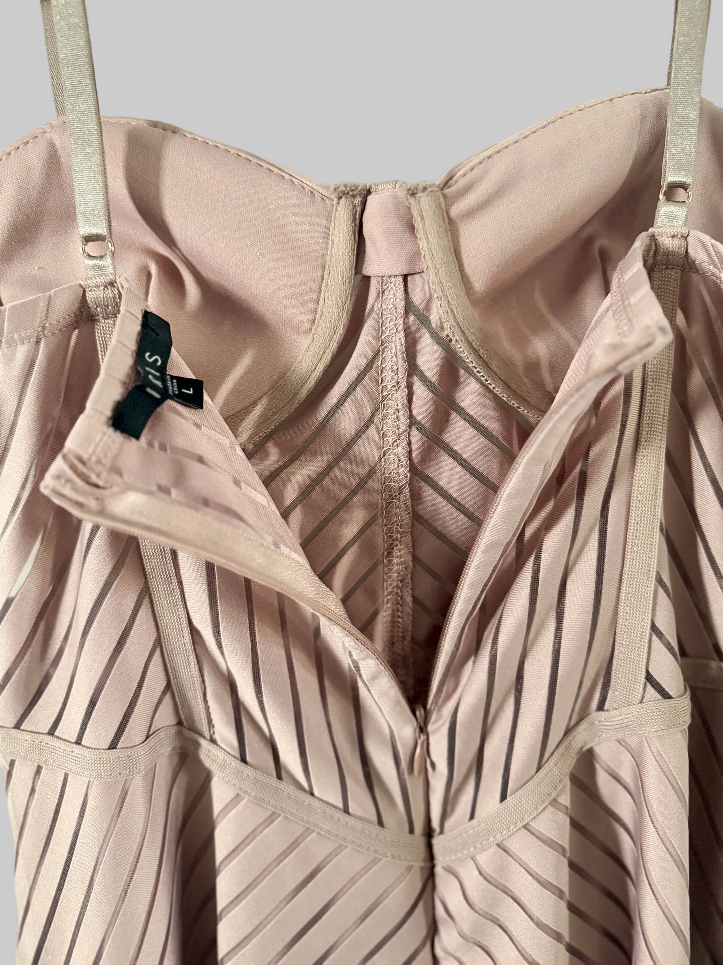 Close-up of a beige bra with a visible brand tag against a light green background