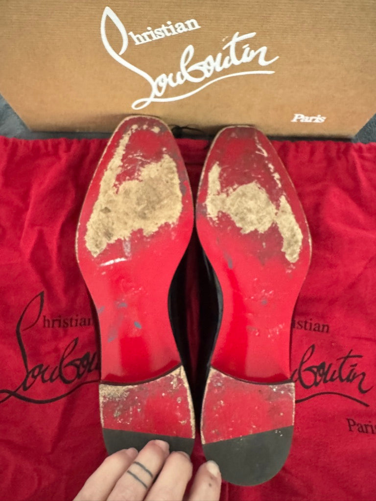 Red soles of Christian Louboutin shoes on a red background with the brand name visible.