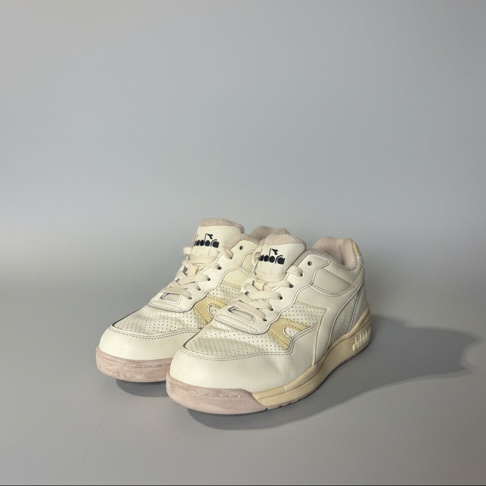 Pair of light-colored sneakers on a white surface with a blurred background