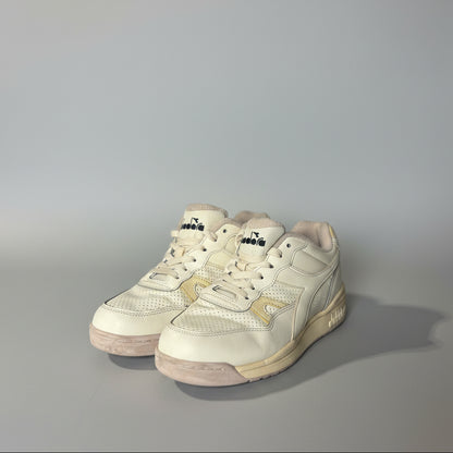 Pair of light-colored sneakers on a white surface with a blurred background