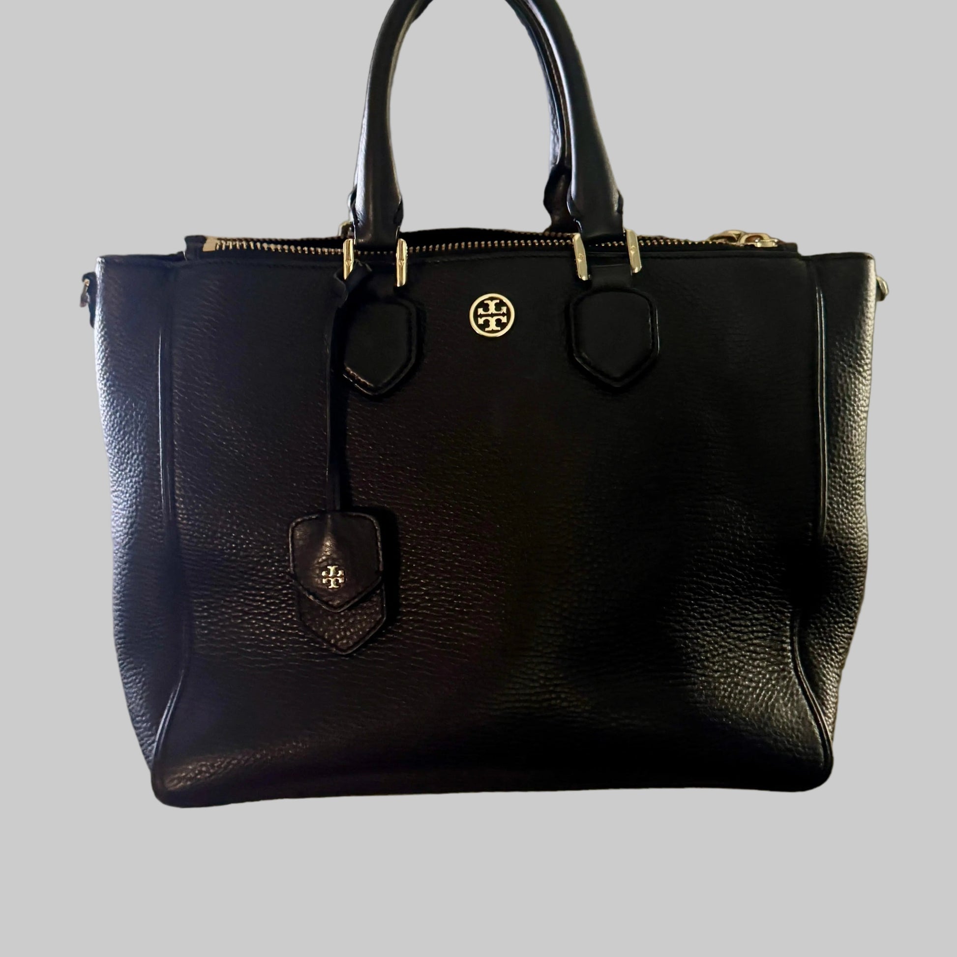 Black handbag held by a person in an indoor setting