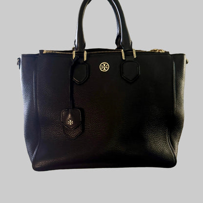 Black handbag held by a person in an indoor setting