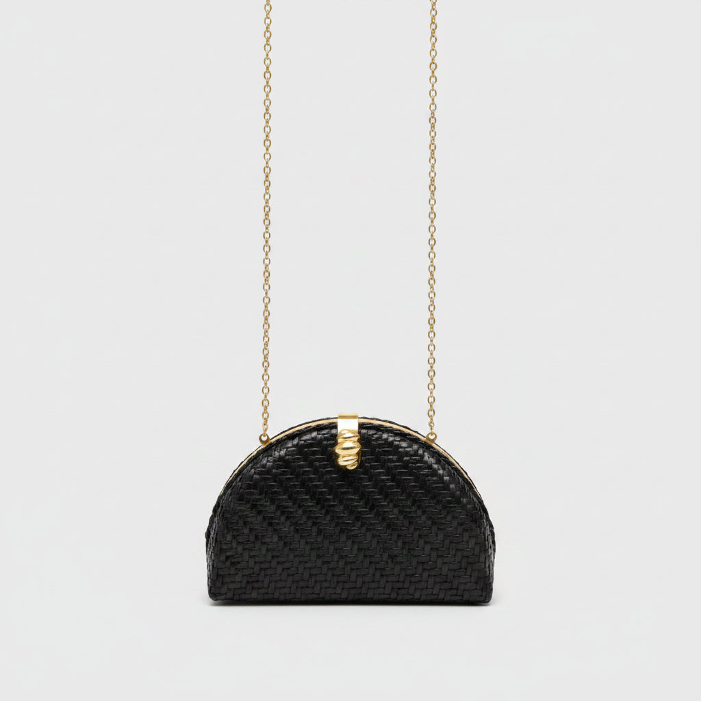 A small black woven handbag with a gold-tone chain strap and a decorative gold clasp, shown against a light gray background.
