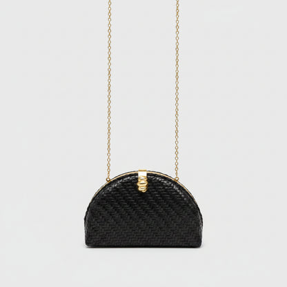 A small black woven handbag with a gold-tone chain strap and a decorative gold clasp, shown against a light gray background.