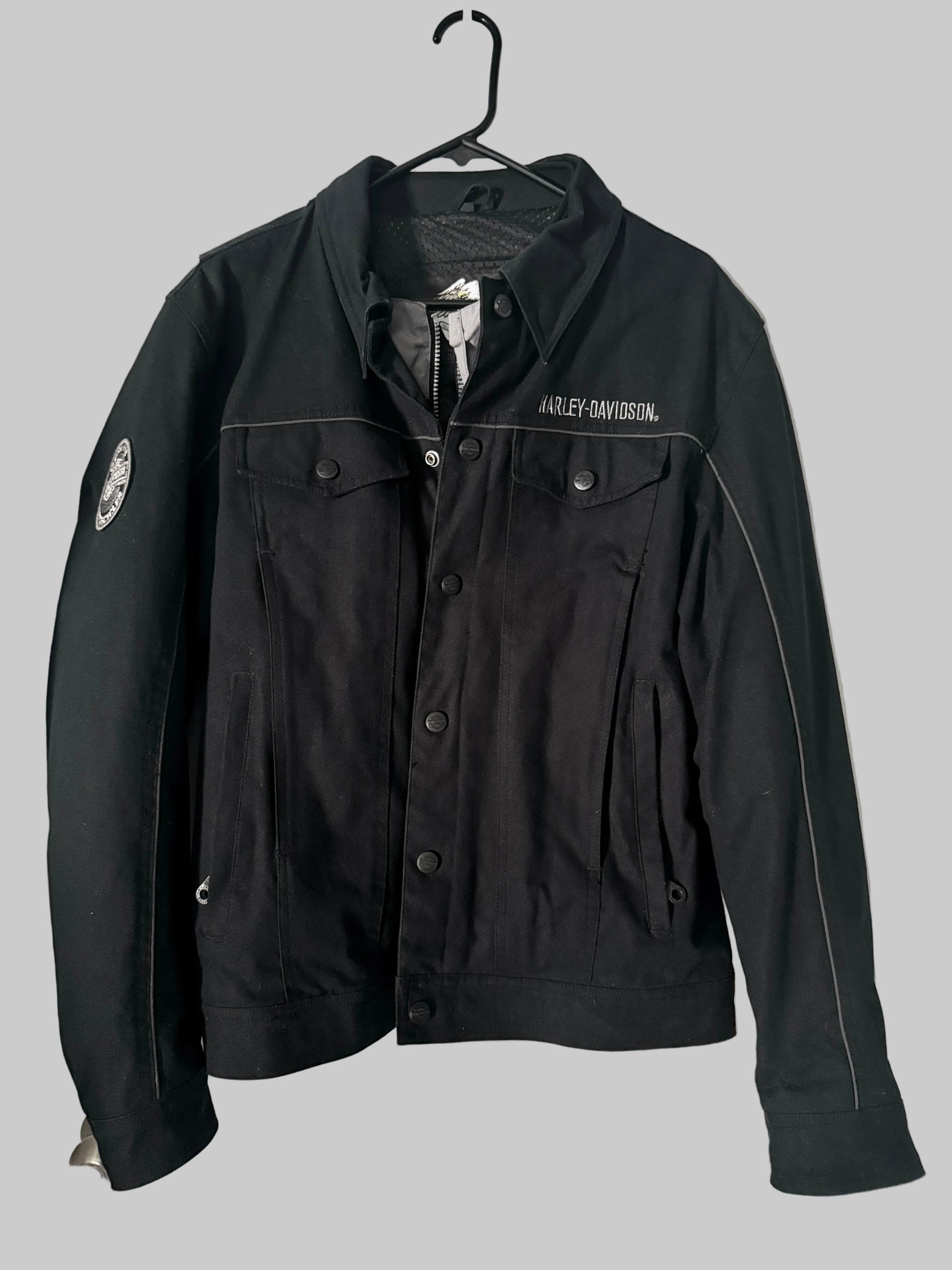 Black jacket with visible branding on a hanger against a white door background