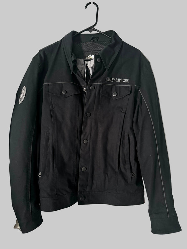 Black jacket with visible branding on a hanger against a white door background