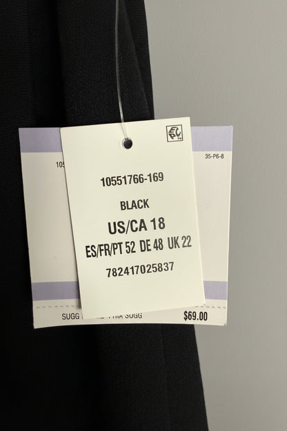 A close-up of a garment tag attached to a black fabric item, showing the text 'BLACK US/CA 18' and size information, with a textured light blue wall in the background.