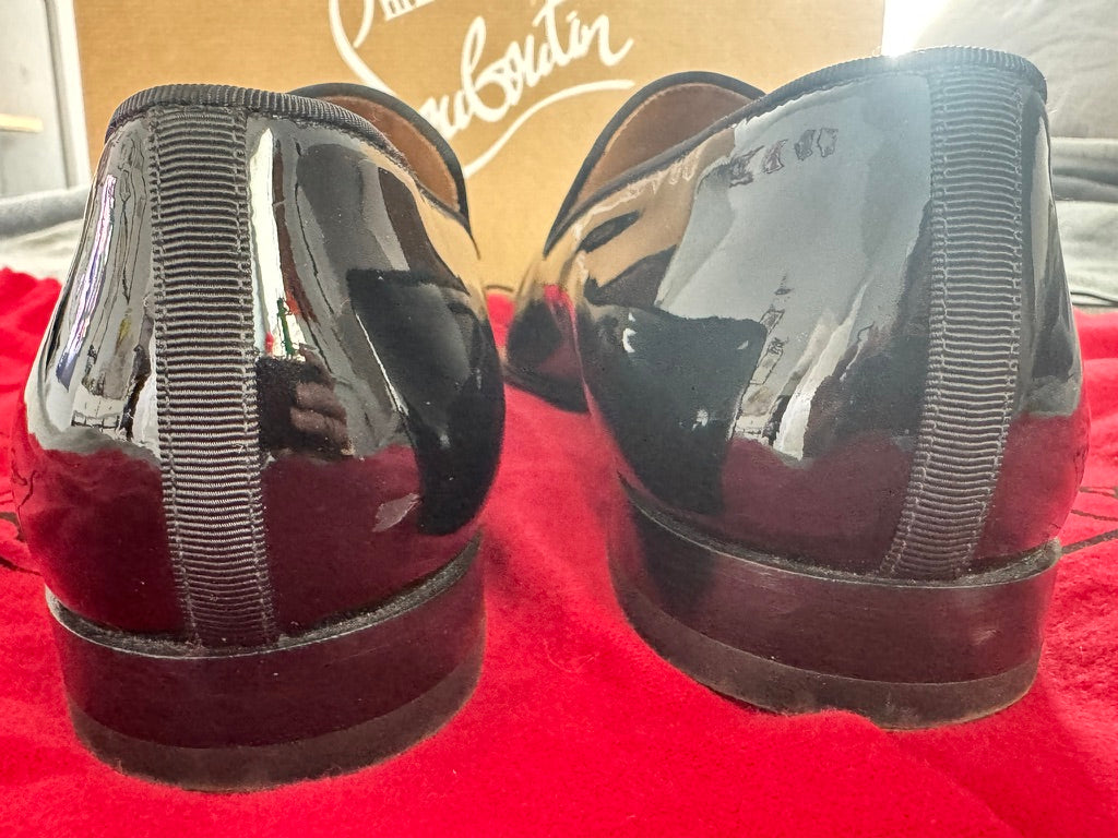 Shiny black shoes on a red surface with a blurred background